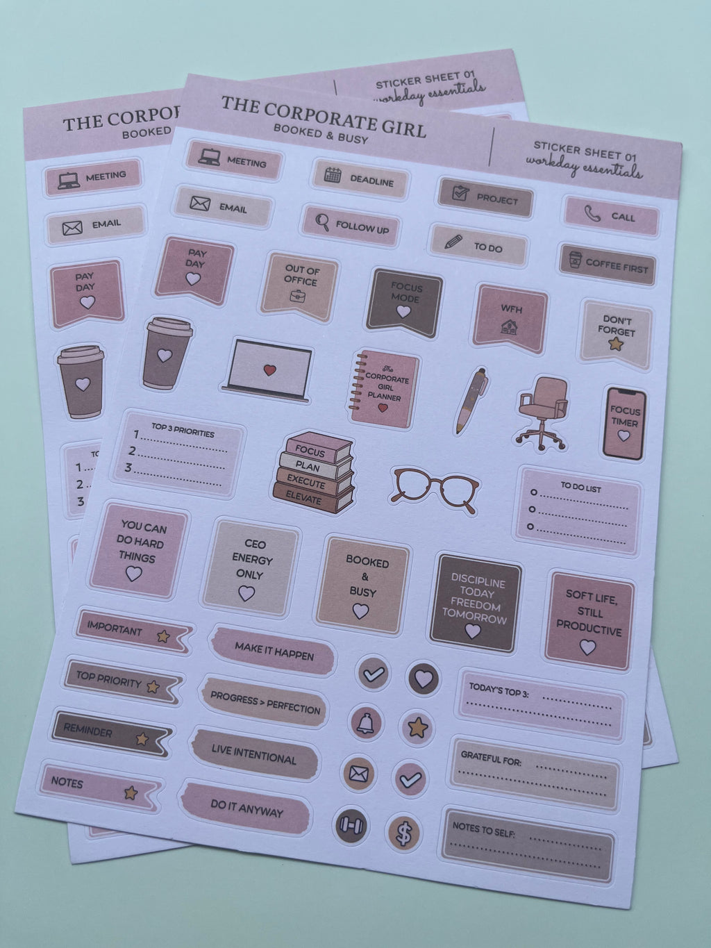 Two sheets of cute office-themed stickers on a pale mint green background. The stickers feature illustrations of coffee cups, notebooks, eyeglasses, and text labels in muted shades of pink, beige, and brown.