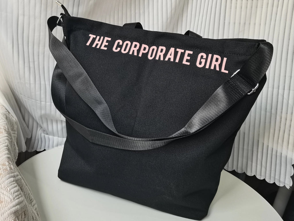 Black tote bag with 'THE CORPORATE GIRL' text on a white surface