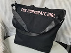 Black tote bag with 'THE CORPORATE GIRL' text on a white surface